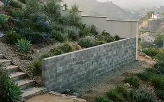 Editorial illustration: Concrete block retaining wall holding a planted slope beside a freestanding stucco garden wall in the Los Angeles hills