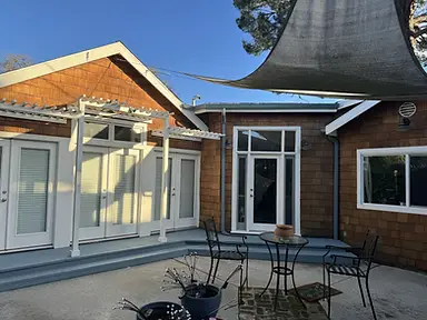 Rear exterior of craftsman home with freshly painted white trim, pergola, blue-painted deck, French doors, and cedar shake siding