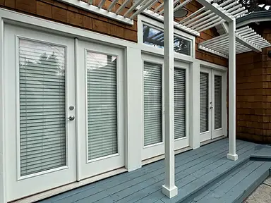 Crisp white painted pergola and door trim contrasting with natural cedar shingles above a newly painted blue-gray wood deck