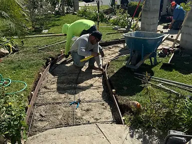 Curved wood forms and reinforcement prepared for a new concrete front walkway across a landscaped yard.