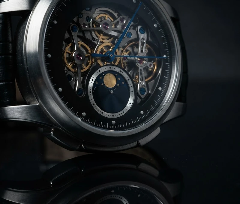 Macro view of luxury mechanical wristwatch with moon-phase complication on obsidian surface