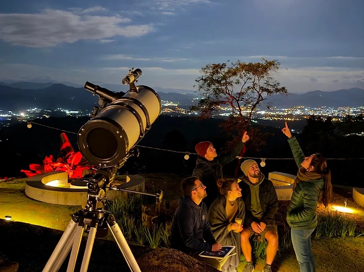Grupo observando o céu com telescópio sob a lua