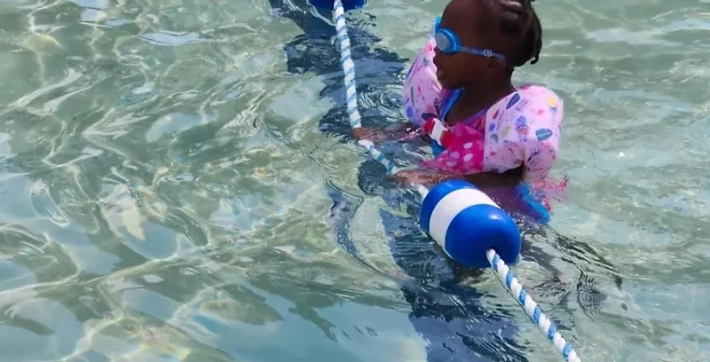 A young swimmer holding a pool lane line during a lesson