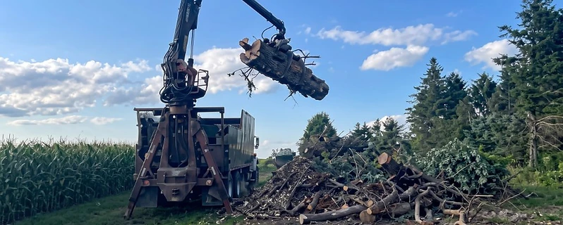 Grapple truck suspending a large log in the air on a southeast Minnesota job site
