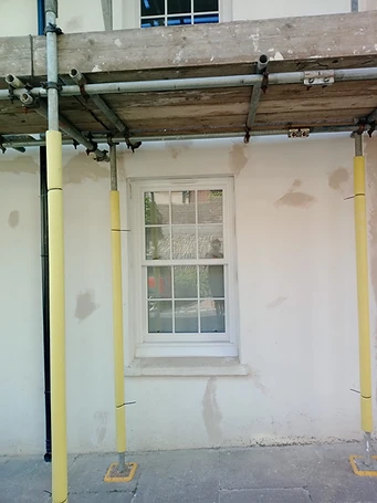 Close-up of ground-floor render — moisture staining and hollow areas