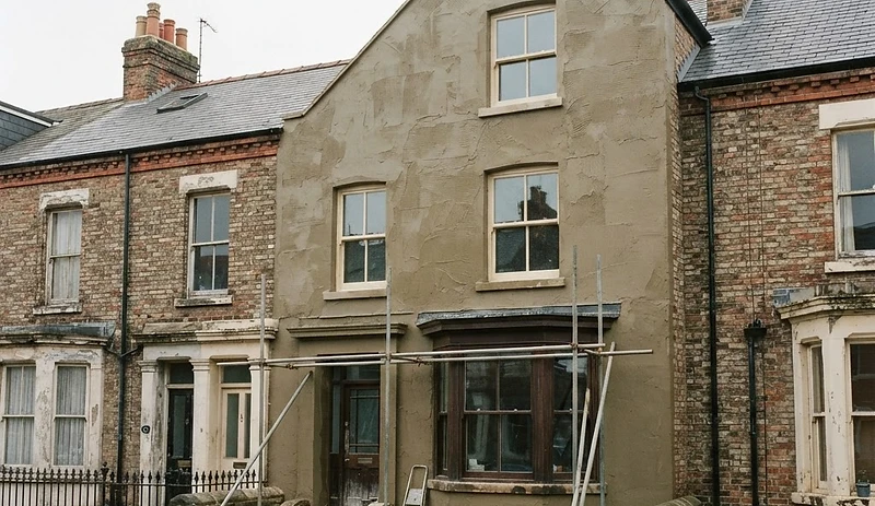 Freshly applied lime render with ruled finishing marks on a Victorian terrace elevation