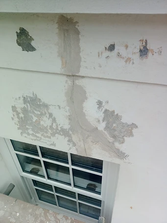 Cracked render at parapet return — failure propagating from cornice joint