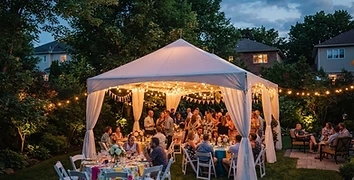 Festive backyard party tent at dusk with warm string lights and round tables