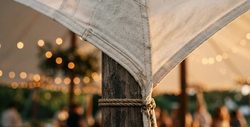 Close-up detail of premium sailcloth tent fabric with fairy light bokeh at golden hour