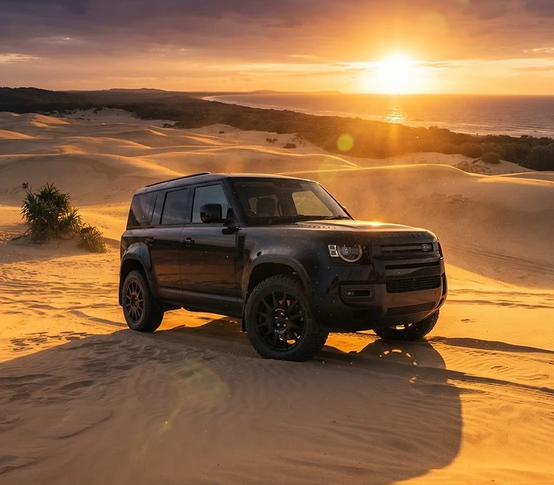 Land Rover Defender on the golden sand dunes of Fraser Island (K'gari) at golden hour
