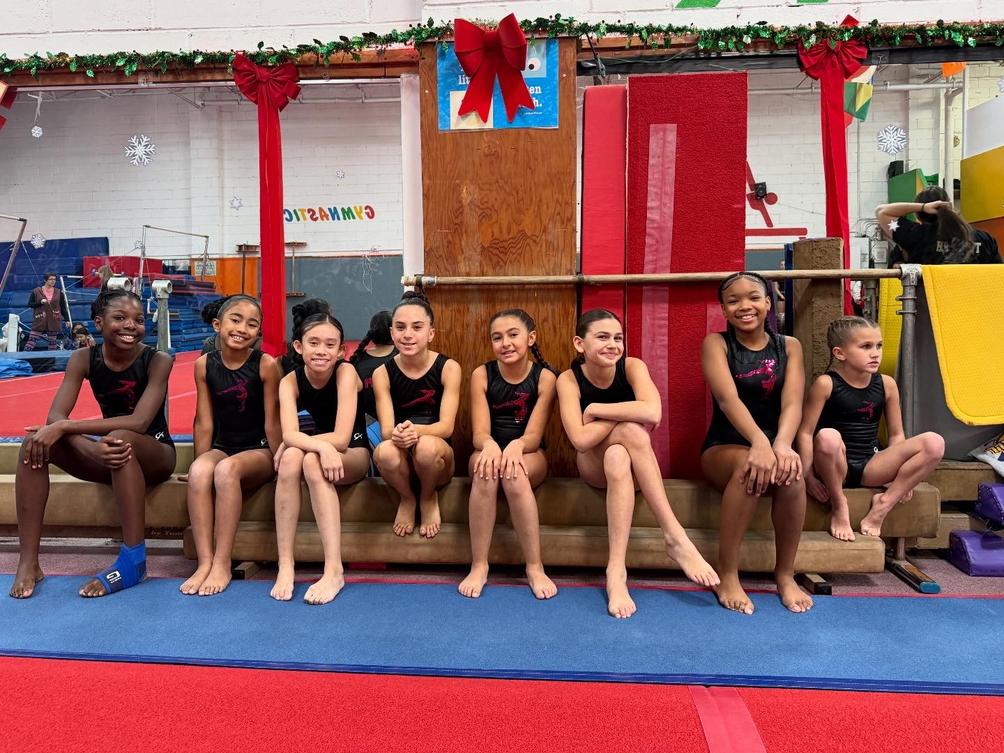 Two gymnasts posing together at a competition with balloon arch