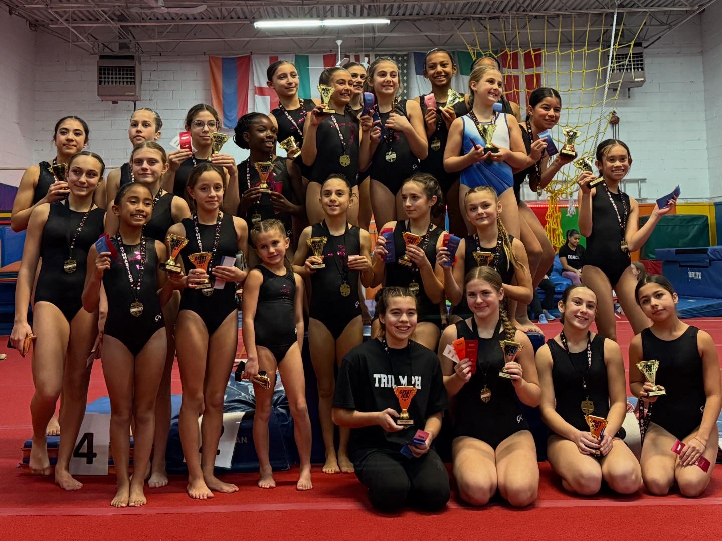 Gymnasts on competition awards podium with medal backdrop