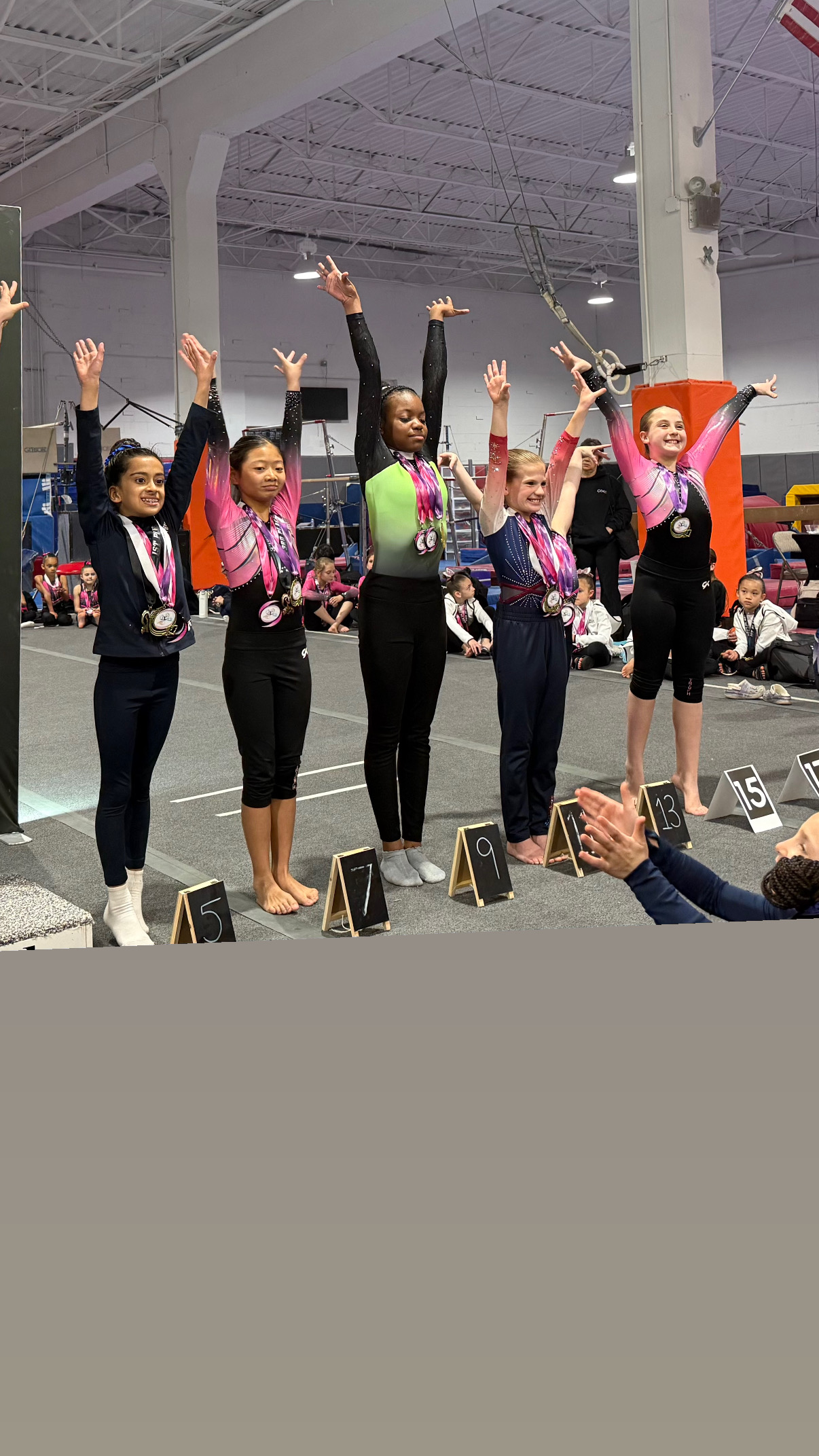 Group of gymnasts with medals raising hands at competition