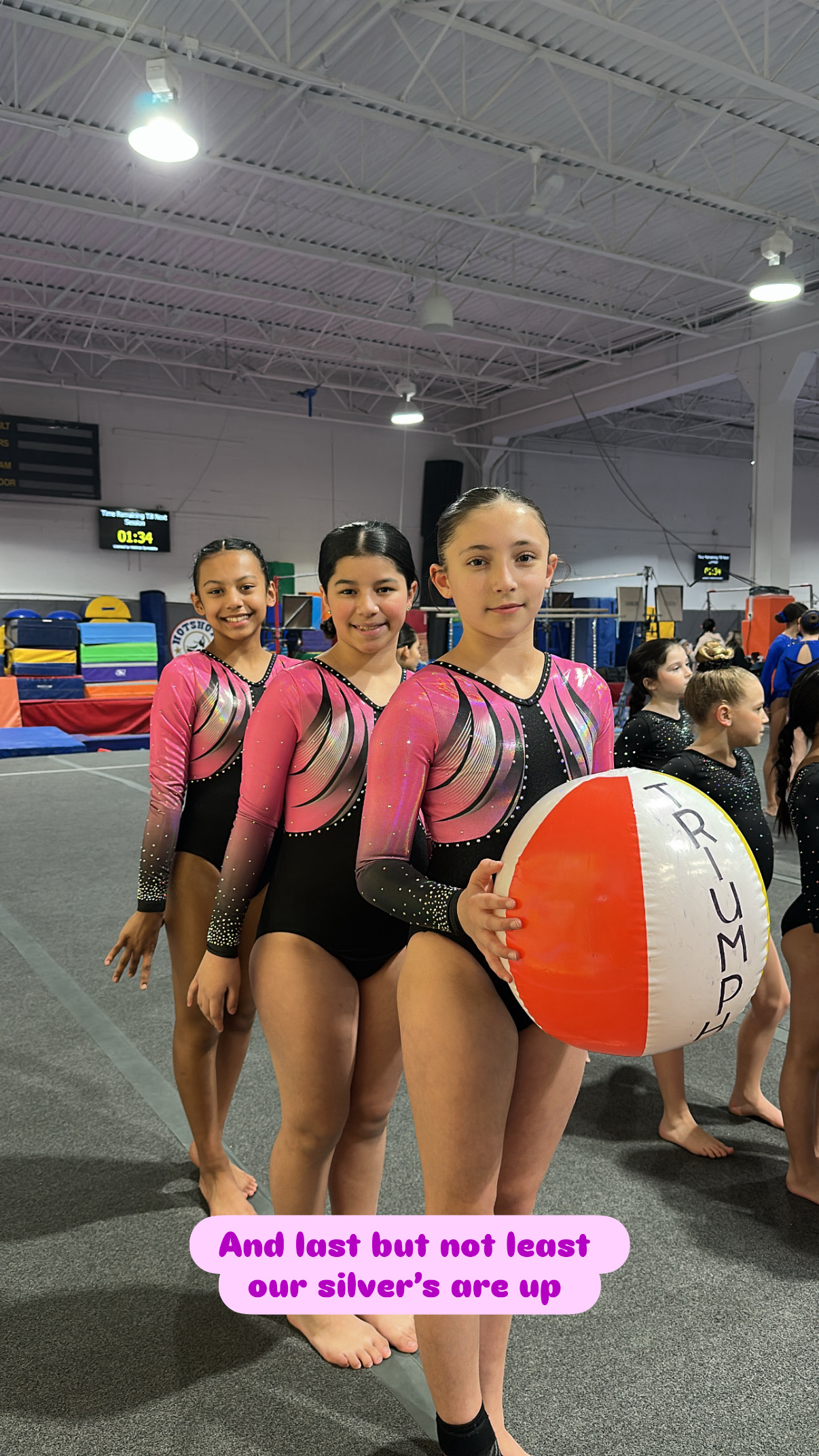 Gymnasts on competition awards stage with red curtain