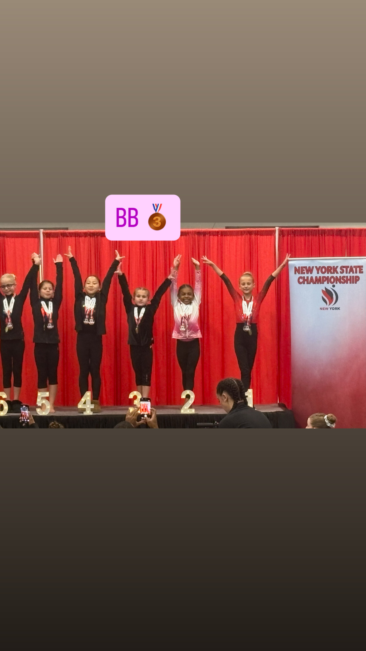 Gymnasts on competition floor podium celebrating placements