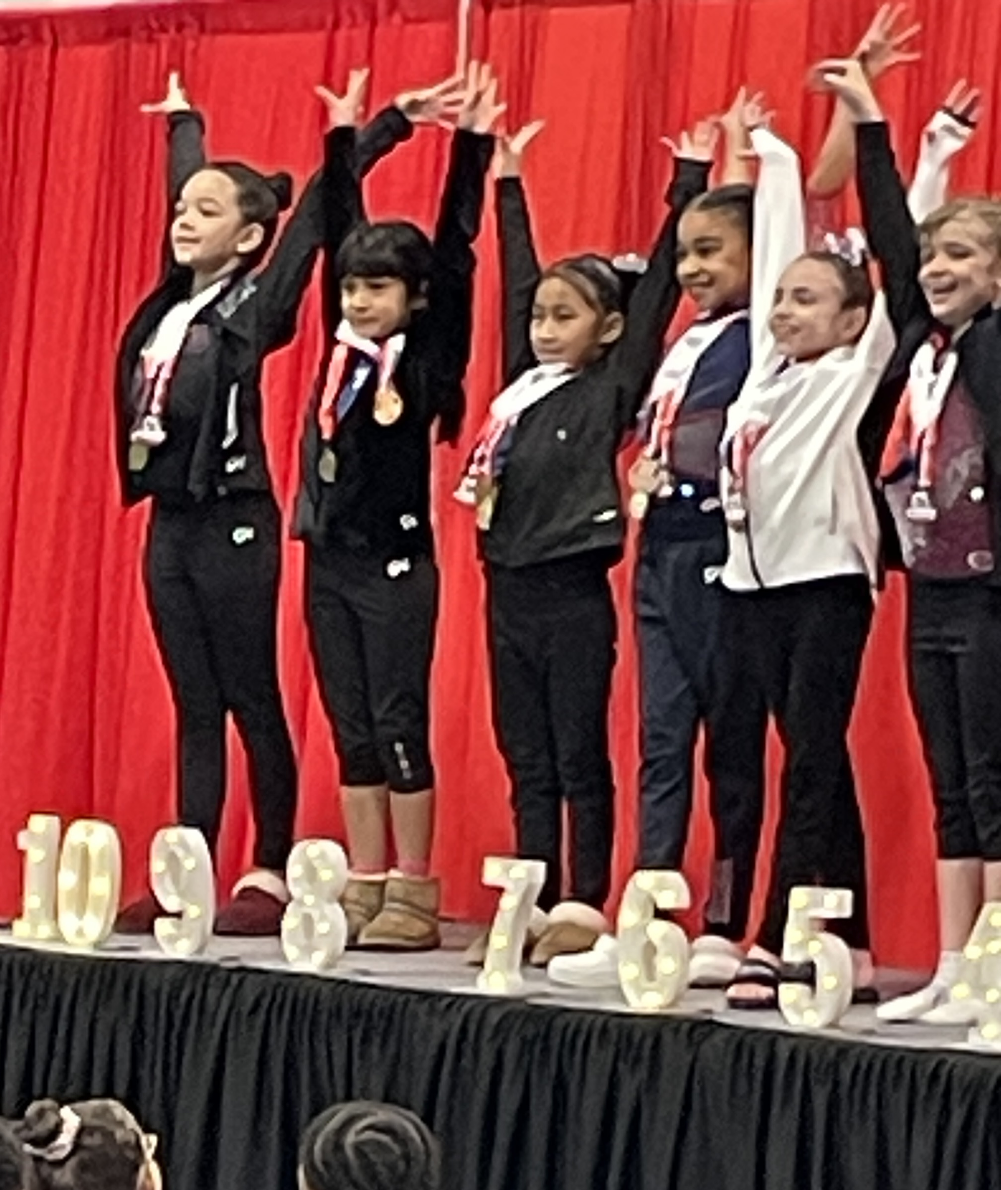Young gymnast with gold medal standing at competition mat