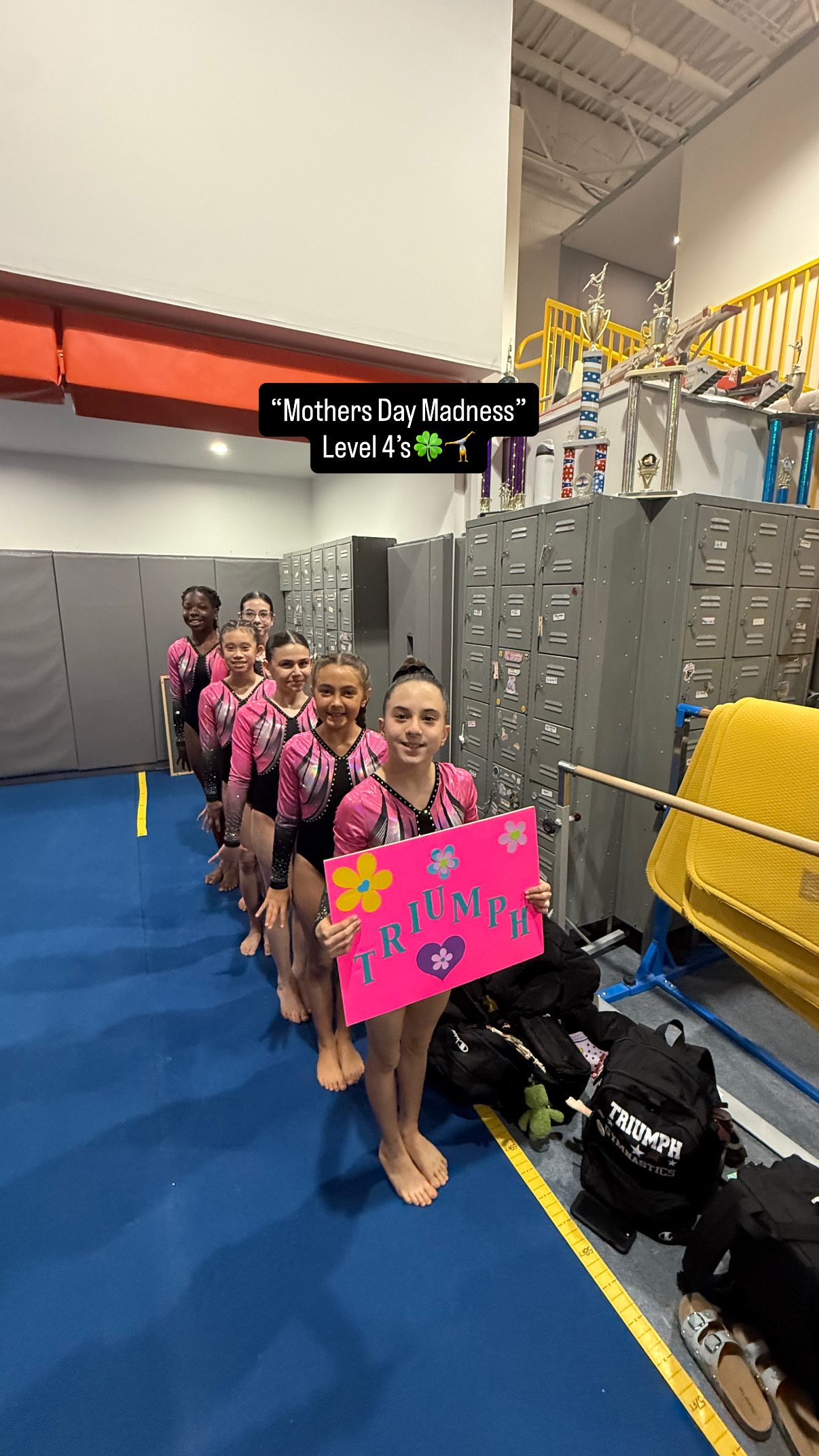 Team gymnasts sitting on gym floor smiling in a row