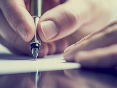 Hands signing a document with a fountain pen