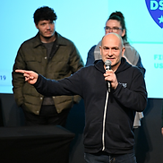 Billy Wimsett speaking and gesturing at a RootsCamp event panel.