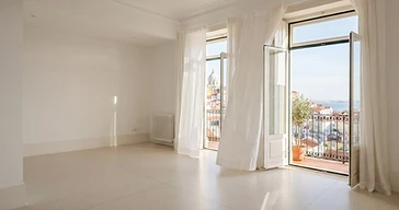 Interior de apartamento moderno em Lisboa com portas de balcão abertas e luz da manhã