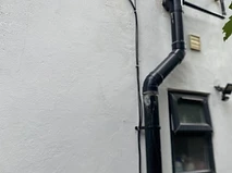CCTV cabling routed cleanly alongside a downspout on an exterior wall