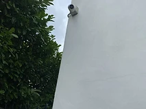 External dome camera mounted near the soffit of a rendered corner wall