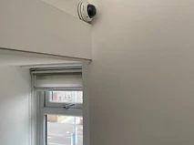 Dome camera mounted in a corridor corner beneath a green emergency exit sign