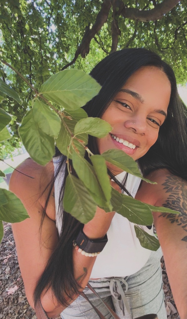 Joi Ramon outdoors, partially framed by a tree branch — embodying the sacred vision of Limitless Soul Healing