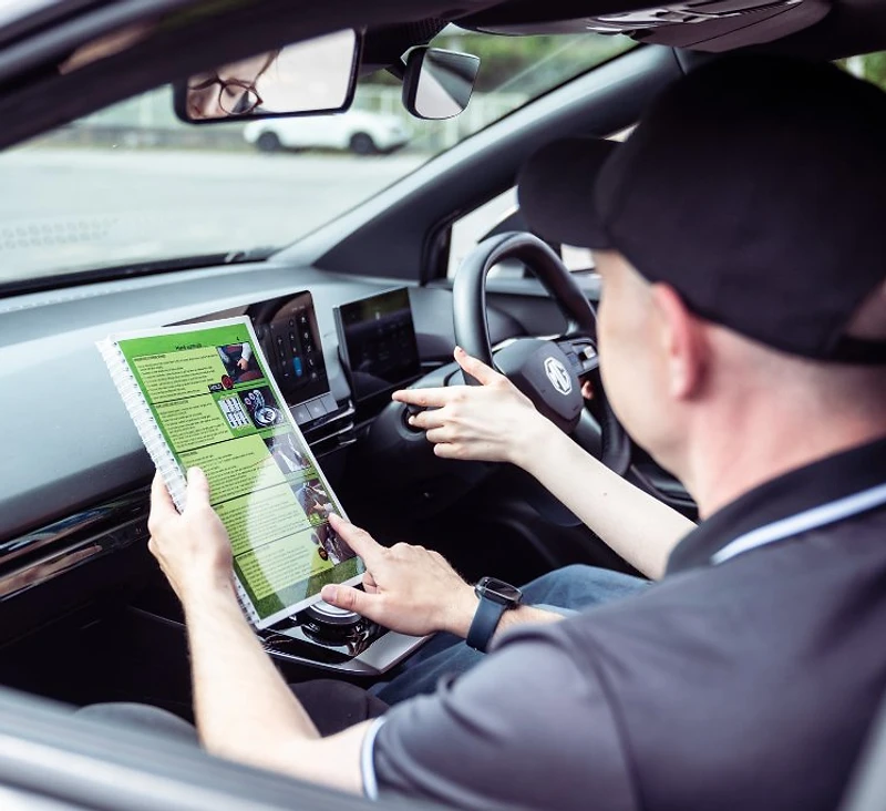 PASS-UK driving instructor talking a learner through the lesson workbook in the car