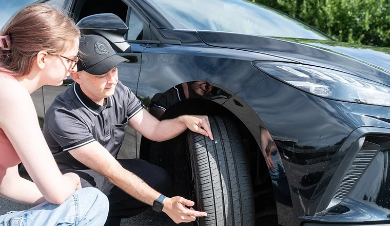 PASS-UK instructor kneeling with a learner to check tyre tread depth