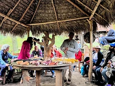 A campesino presents varieties of maize criollo under a palapa to gathered students and community members