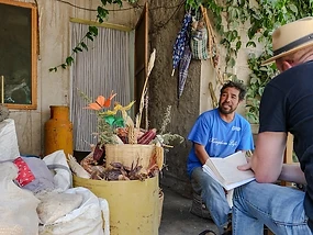 Kyle Piispanen during ethnographic fieldwork beside a display of native maize
