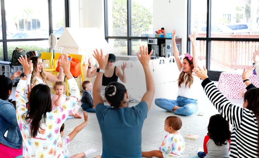 Caregiver-and-me enrichment class with hands raised in play