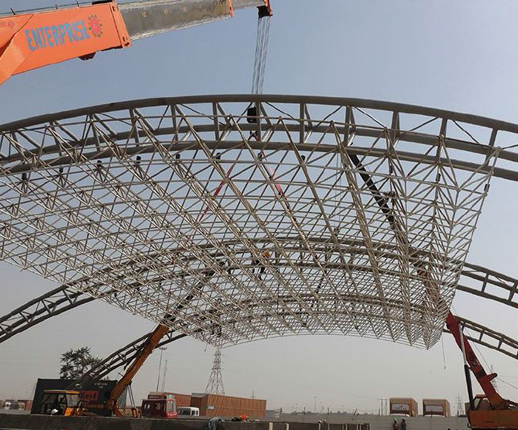 Space frame roof being hoisted by crane
