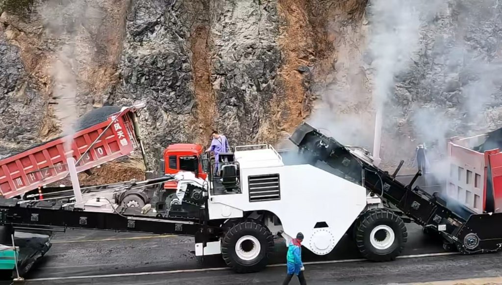 Receiving hot mix from dump truck on highway project