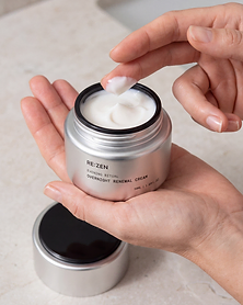 Open jar of RE:ZEN Overnight Renewal Cream held in one hand