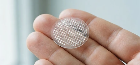 A Pacheez microneedle patch resting on a person's fingertips