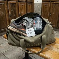 Open gym bag with running shoes, towel, water bottle and a PACHEEZ sachet naturally placed inside