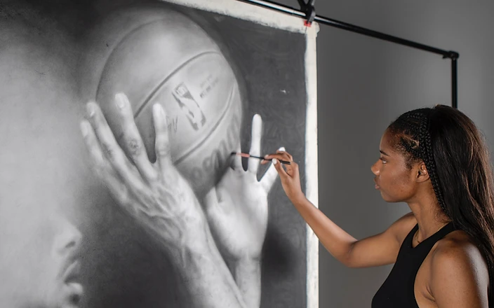 Anaïa working on a charcoal portrait of a basketball player