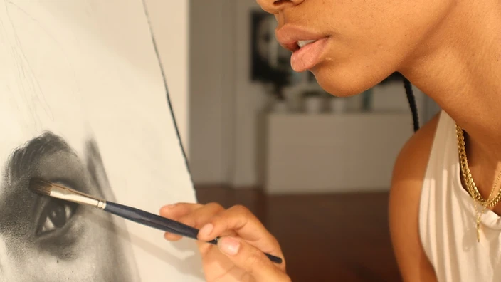 Artist seated before large portrait canvases with basketball on studio floor