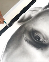 Artist drawing at close range, brush to charcoal portrait