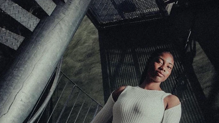 Anaïa beside a metal staircase, holding a basketball
