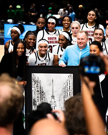 Basketball players gathered around a framed drawing of the Eiffel Tower