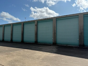 Row of drive-up storage units with teal roll-up doors at Challenger Storage