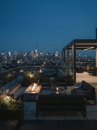 Premium apartment rooftop lounge and amenity space at blue hour with fire pit and lounge seating