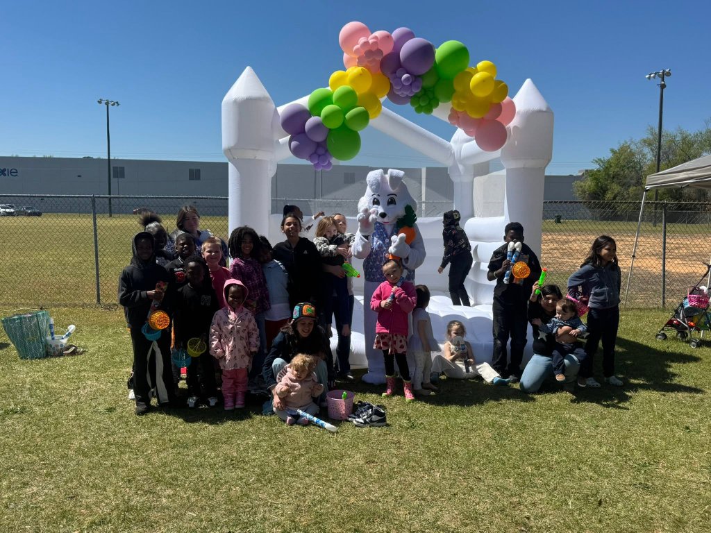Group photo with white bounce house and balloon arch