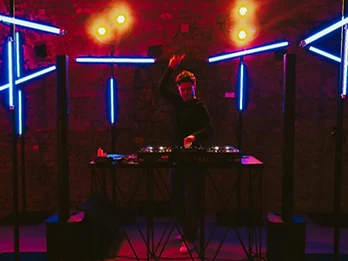 DJ con braccio alzato tra luci rosse e blu