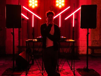 DJ in controluce rossa tra archi