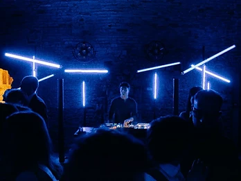DJ con light rig blu neon e pubblico in controluce