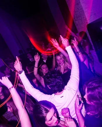 Pubblico con le mani alzate sotto luci magenta
